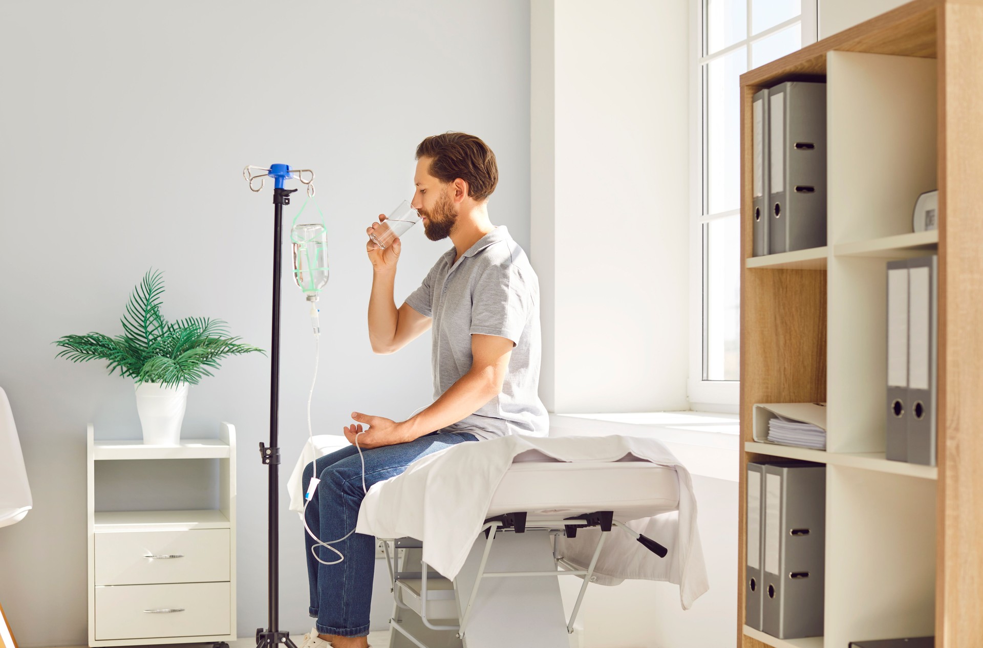 Man sitting at doctor's office in clinic while receiving IV drip infusion and vitamin therapy